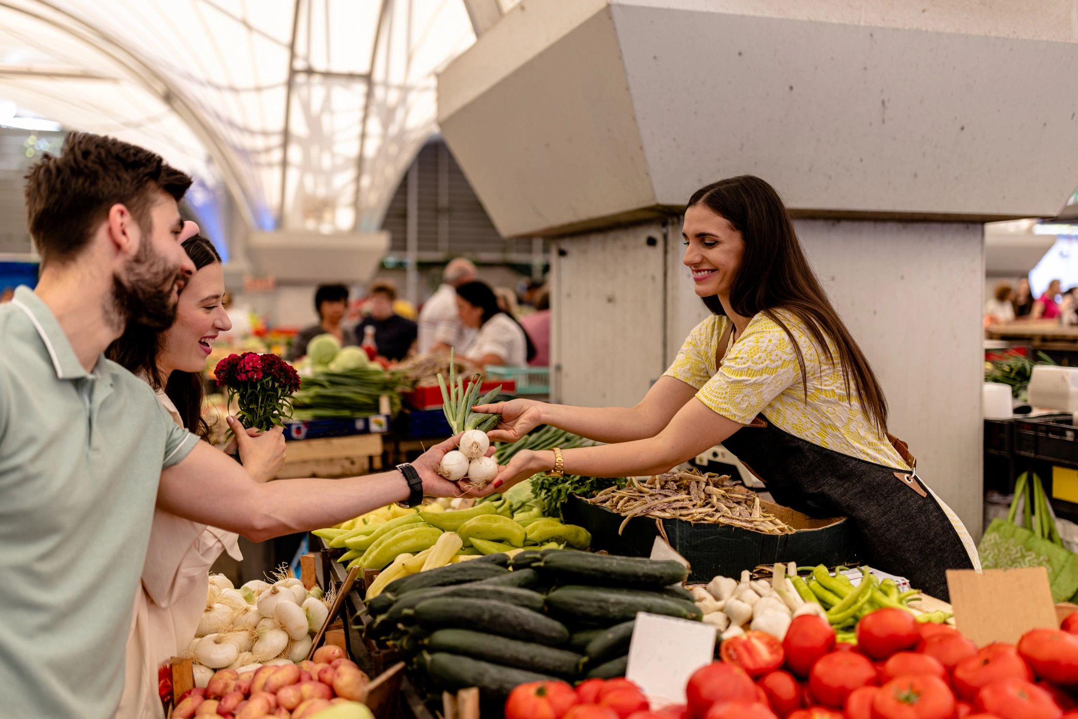Customers choosing vegetables from a market vendor